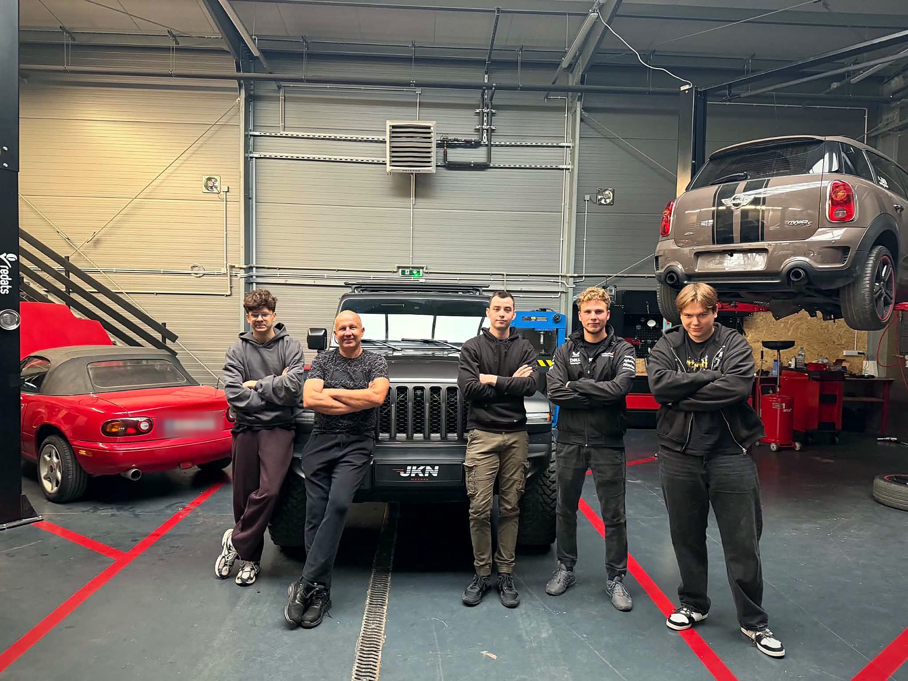 Zespół JKN Motors w hali, przed Jeepem z tablicą JKN Motors